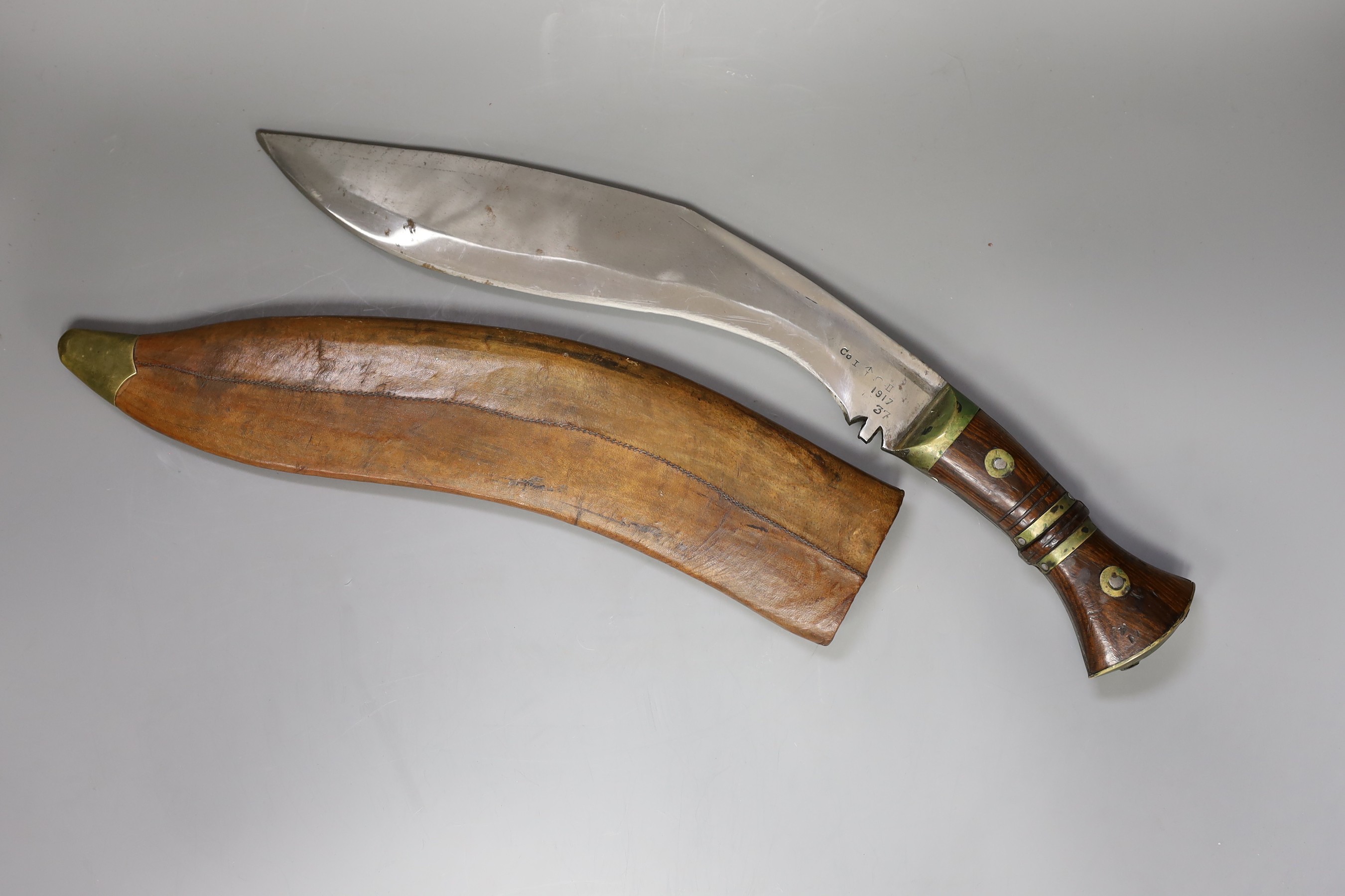 A large Kukri in with brass mounted wooden handle and leather wooden case, 54cm long